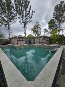 a swimming pool with blue water and trees in the background at Aamara in Bangalore