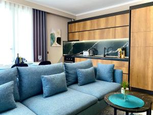 a living room with a blue couch and a kitchen at EKA Luxury Beachfront Apartments in Vlorë