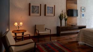 a bedroom with a bed and a tv and a chair at Oratório Pousada Boutique in Tiradentes