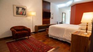 a hotel room with a bed and a chair at Oratório Pousada Boutique in Tiradentes +37 photos