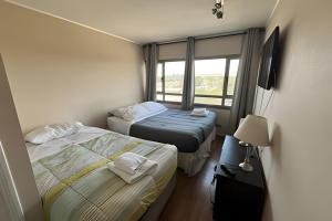 two beds in a small room with a window at Departamento en Calama in Calama