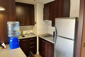 a kitchen with a white refrigerator and wooden cabinets at Departamento en Calama in Calama