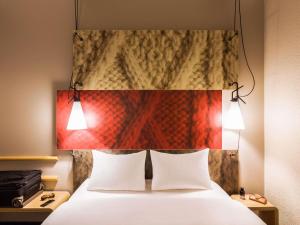 a bedroom with a bed with two white pillows and two lamps at ibis Winterthur City in Winterthur