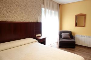 a bedroom with a bed and a chair and a mirror at La Calma Candás in Candás