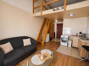 a living room with a black couch and a kitchen at Apartamenty Green Garden z ogrodem i przyjazne dla zwierząt, Racibórz in Racibórz
