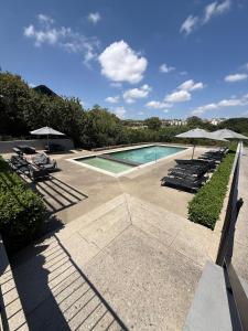 a swimming pool with lounge chairs and umbrellas at The Precinct Lifestyle in Midrand