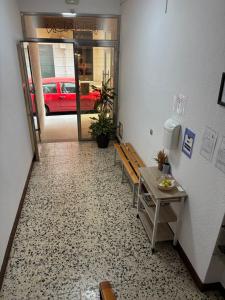 a hallway with a table and benches and a red car at Pensión Las Arenas in Vilagarcia de Arousa