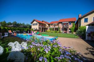 a house with a swimming pool in a yard with flowers at Villa Mare Apartamenty in Grzybowo