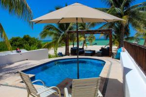 a swimming pool with an umbrella and chairs and a beach at Villa Siros de 4 habitaciones in Chicxulub