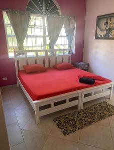 a bedroom with a large bed with red sheets and a window at Pondbottom Apartments Hotel in Saint James