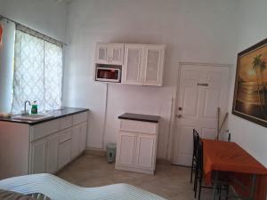 a kitchen with white cabinets and a table and a sink at Pondbottom Apartments Hotel in Saint James +18 photos