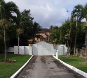a house with a white fence and a driveway at Pondbottom Apartments Hotel in Saint James