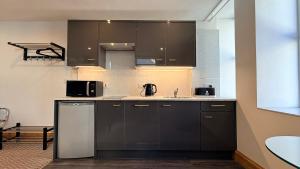 a kitchen with black cabinets and a sink at Crystal House in Barmouth