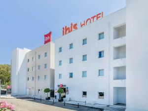 a white hotel with a red sign on it at Hotel ibis Lisboa Alfragide in Lisbon