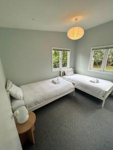 two beds in a room with two windows at Oneroa Manuka Residence in Waiheke Island