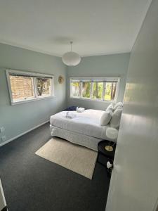 a bedroom with a large bed and two windows at Oneroa Manuka Residence in Waiheke Island +1 photo