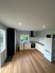 a kitchen with a white refrigerator and wooden floors at Oneroa Manuka Residence in Waiheke Island