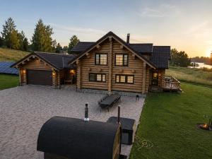 a log cabin with a patio in front of it at Private lakeside holiday house with fireplace, sauna, hot tub - Ezernams Dzintars in Valdemārpils