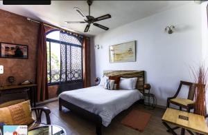 a bedroom with a bed and a ceiling fan at Maison Sahel - African Art & Coastal Serenity in Dakar +61 photos