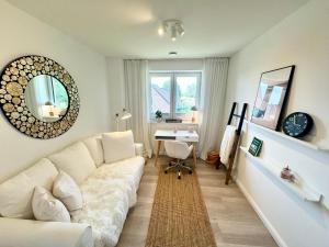 a living room with a white couch and a desk at Vollmöblierte hochwertige neue Apartments in Klevendeich