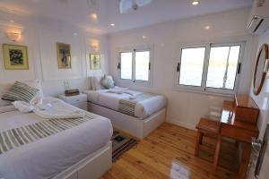 a bedroom with two beds and a desk and windows at Three pyramids Dahabiya in Esna +9 photos
