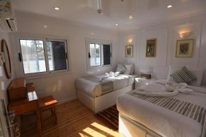 a white bedroom with two beds and a couch at Three pyramids Dahabiya in Esna