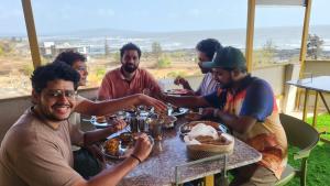 a group of people sitting around a table eating food at Sukhavasam Beach Resort in Adgaon