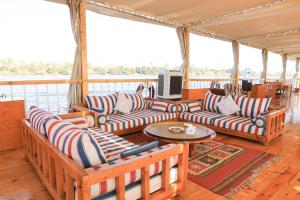 a porch on a boat with couches and a table at Three pyramids Dahabiya in Esna