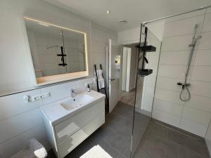 a bathroom with a sink and a glass shower at Vollmöblierte hochwertige neue Apartments in Klevendeich +3 photos