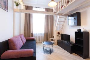 a living room with a couch and a tv and a staircase at Giedres Old Town Apartments in Kaunas
