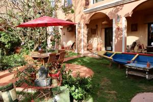 a patio with a table and an umbrella and a boat at Maison Sahel - African Art & Coastal Serenity in Dakar