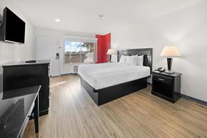 a hotel room with a bed and a flat screen tv at Ramada by Wyndham Ontario Airport & Convention Center in Ontario