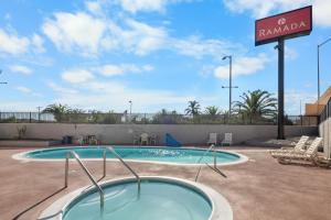 a swimming pool at a resort with a sign at Ramada by Wyndham Ontario Airport & Convention Center in Ontario