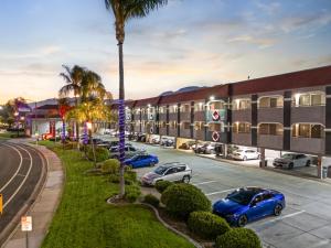 a row of cars parked in a parking lot in front of a building at Ramada by Wyndham Ontario Airport & Convention Center in Ontario