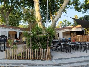 an outdoor patio with tables and chairs and trees at Mobil Home AGDE Hérault in Agde