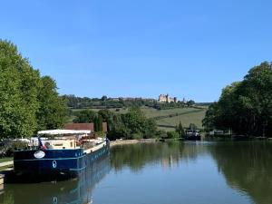 a blue boat on a river with a castle in the background at La Parenthèse Bourguignonne in Savigny-lès-Beaune