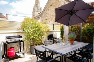 a patio with a table and an umbrella and a grill at La Parenthèse Bourguignonne in Savigny-lès-Beaune