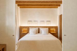 a bedroom with a bed with white sheets and pillows at Convent de la Missio - Grand Luxury Boutique hotel, Adults Only in Palma de Mallorca +75 photos