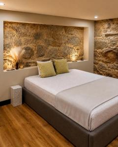 a bedroom with a large bed with a stone wall at Fagundes Village in Valença +56 photos