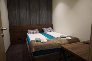 two twin beds in a small room with a desk at LUNAS Apartmani 7 in Kopaonik
