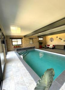 a large swimming pool in a house with a leaf on the floor at La Maison Belle in Germigny