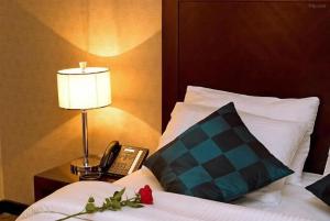 a bed with a lamp and a phone on a table at Vercure Hotel فندق فيركيور جده الحمراء in Jeddah