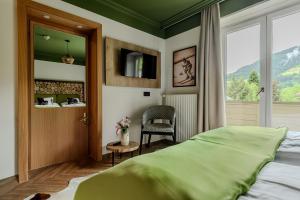 a bedroom with a bed and a chair and a window at Hotel Völserhof - Bergbahn im Sommer 2026 inklusive in Bad Hofgastein +110 photos
