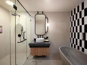 a bathroom with a sink and a mirror and a tub at Tribe Bali Legian in Legian +7 photos