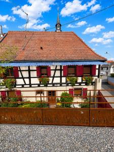 a building with red and white windows and a fence at Duplex rénové avec terrasse privative à 10 mm de Colmar et Eguisheim, à 2 mm du grand axe autoroutier Strasbourg Mulhouse in Sainte-Croix-en-Plaine