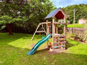 a wooden playground with a slide and a house at Apartmány CHATTA in Horní Maršov