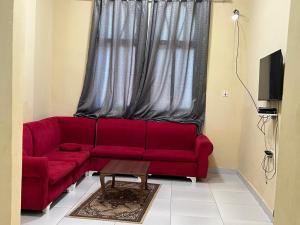 a red couch in a living room with a window at Aluruba Residence in Mogadishu