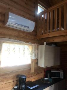 a kitchen with a microwave and a window in a log cabin at Saimaanranta mökki in Kokkoniemi