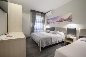 a hotel room with two beds and a window at Hotel Anna in Siena