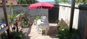 a patio with a table and a red umbrella at Erina Beach in Antalaha